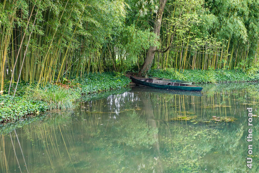 Die Bambusinsel in Monets Wassergarten mit Boot und Spiegelung. Bei einem Besuch von Monet's Garten im Frühling sind erst vereinzelte Blätter von Seerosen im Teich zu sehen.