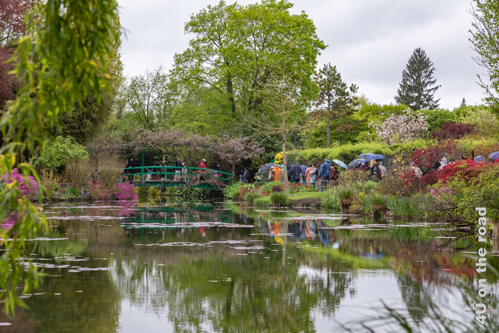Geduldig warten die Menschen im Regen darauf, dass sie an der Reihe sind, die Brücke zu betreten, die Monet in seinem Garten in Giverny im berühmten Bild "Seerosenteich mit der japanischen Brücke" festgehalten hat.