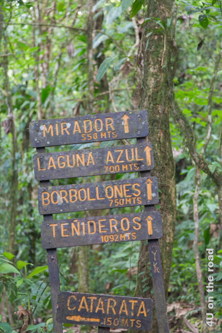 Ein einfacher Holzwegweiser im Nationalpark des Vulkan Tenorio zeigt die Entfernungen zum Aussichtspunkt, der blauen Lagune und den Wasserblubbern. 