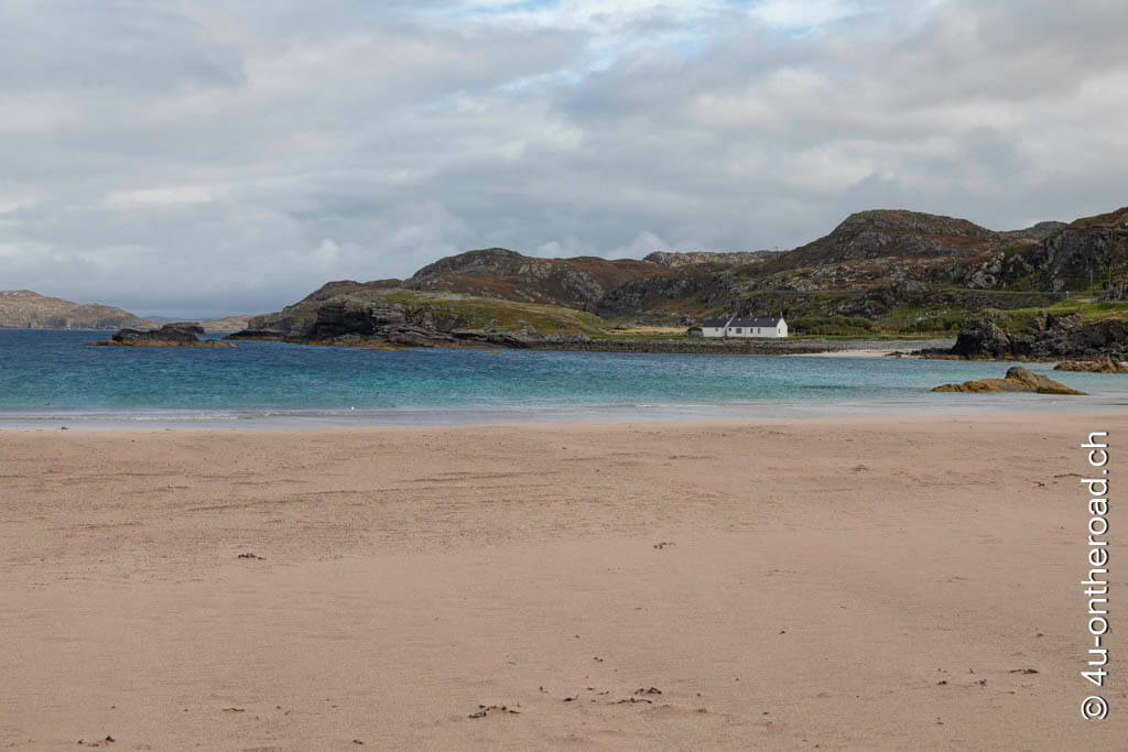 Ein weisses Haus vor schottischen Bergen, ein türkisblaues Meer und der rosa Strand. Immer wieder schön. Mit dem Wohnmobil durch Schottland