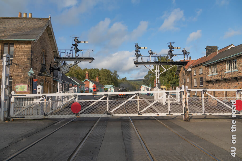 Der Bahnhof von der Strasse aus gesehen mit seinen Signalen, der alten Bahnhofsuhr und den geschlossenen Schiebetoren während die Dampflok einfährt.