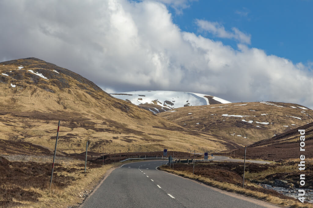 Die Cairngorms noch mit Schnee auf der Hügelkuppe. Strasse von Balmoral nach Braemar.